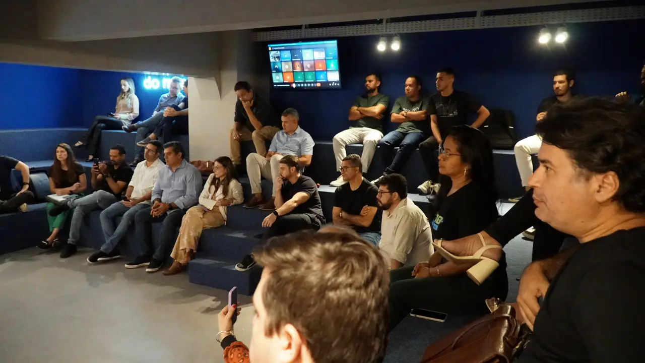 Participantes da JoInT sentados em arquibancada interna durante evento pontes de oportunidade na Ampla Comunicação no Empresarial ITBC.